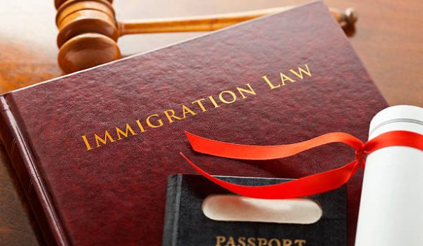 Leather bound Immigration Law book with gold embossed type with a judges gavel, legal document and a passport.